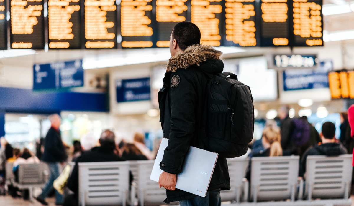 A man carrying a folder checks his flight status in the airport