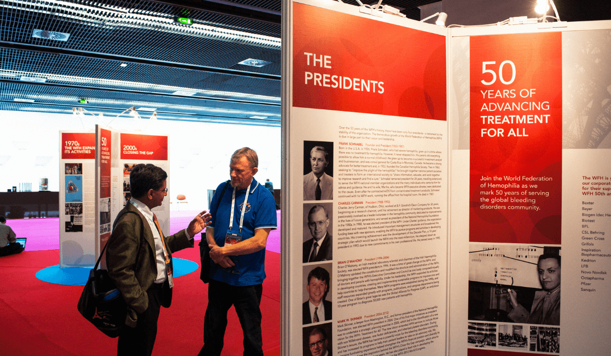 Two people converse in front of banners showing the history of the WFH