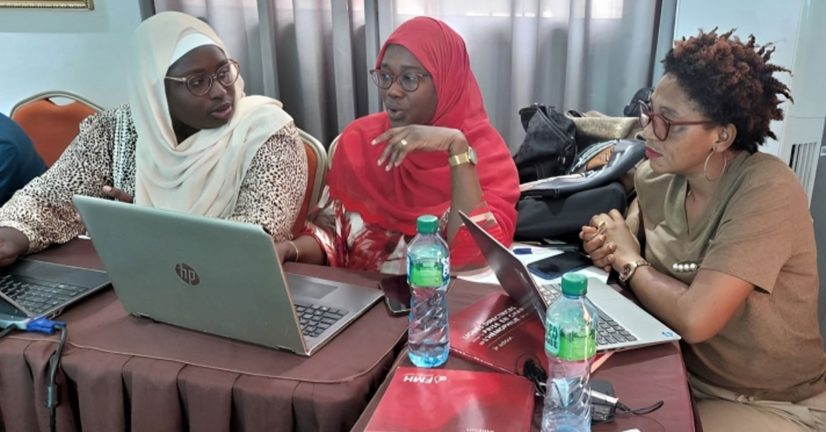 Three women gathered around laptops have a discussion