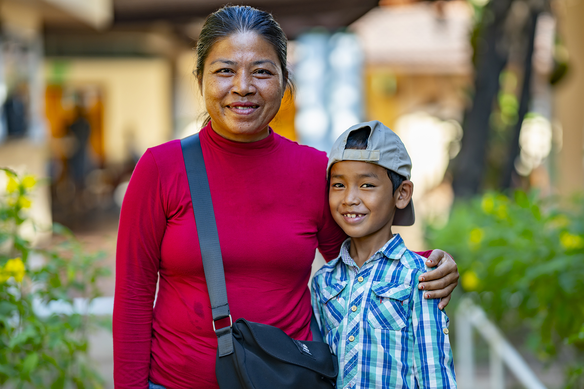 Une mère sourit en entourant son fils de son bras.