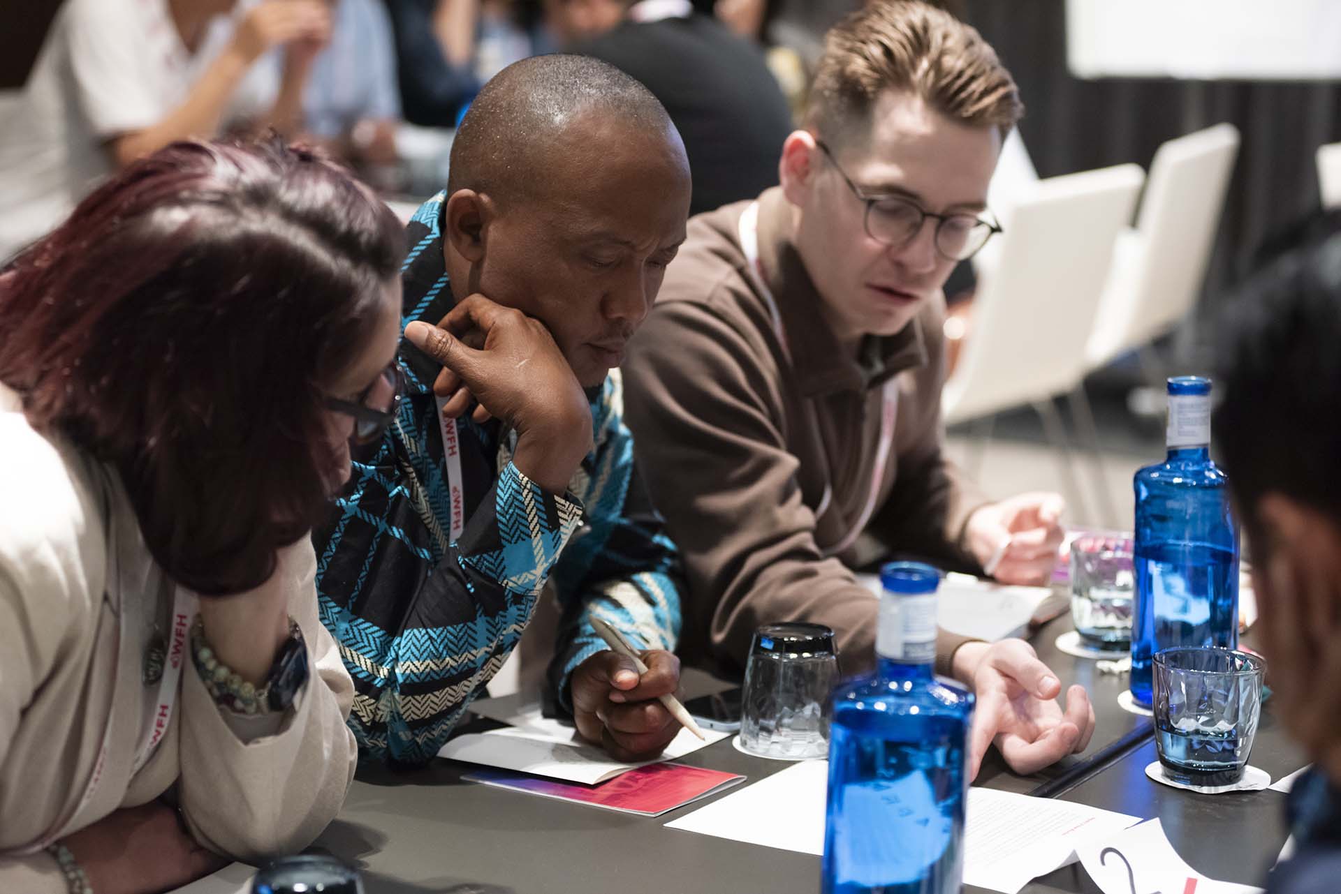 Three people sitting at a table review information on a handout.